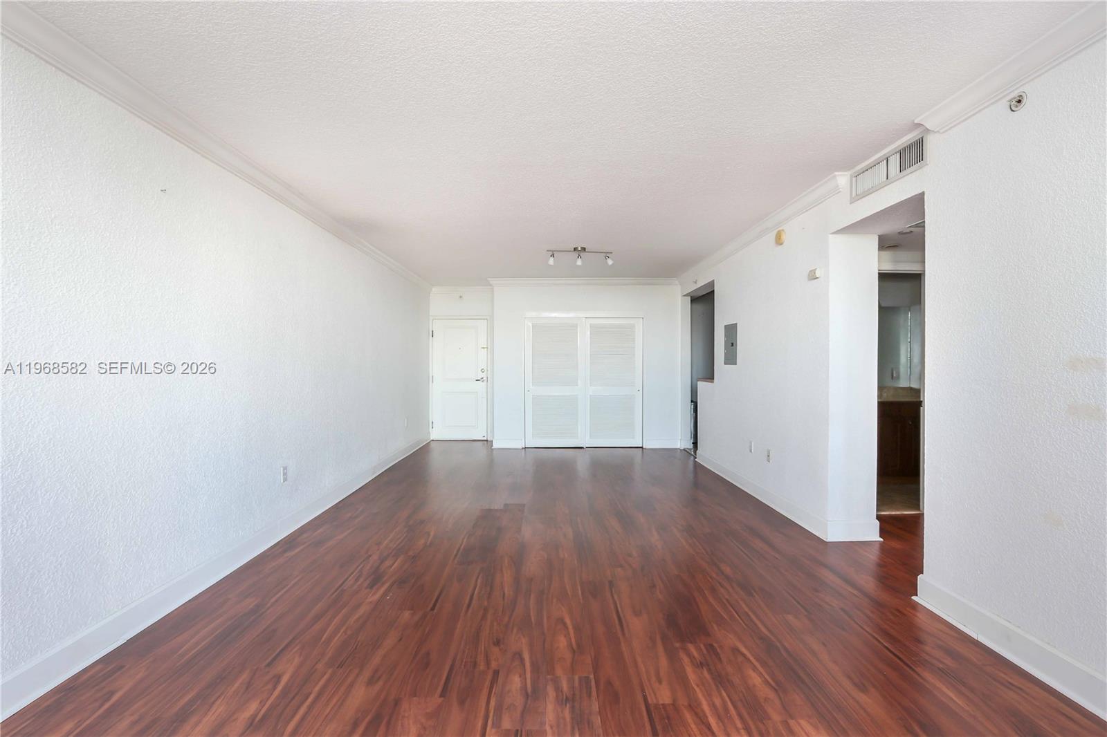 An empty room features white walls, crown molding, and dark wood-look flooring — 401 69 ST # 411, Miami Beach FL 33141, MIAMI BEACH, FL