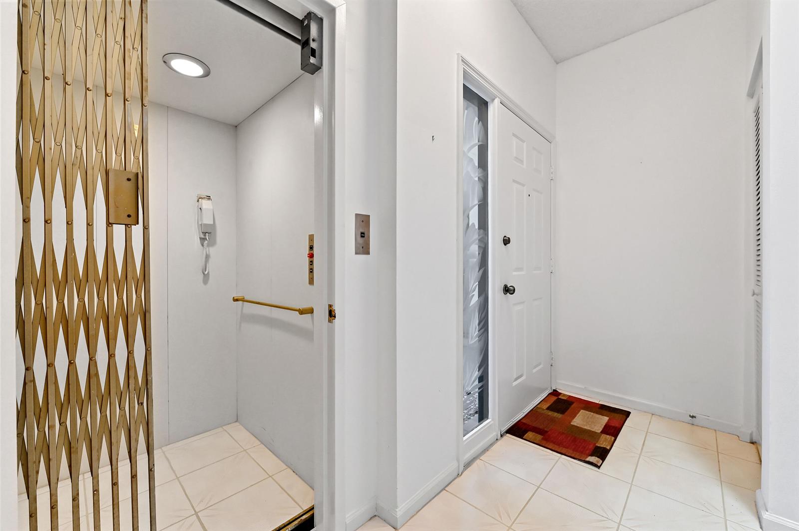 An entryway features a white door with a side window, tile flooring, and an elevator — 11618 Briarwood Circle # 4, Boynton Beach FL 33437, BOYNTON BEACH, FL
