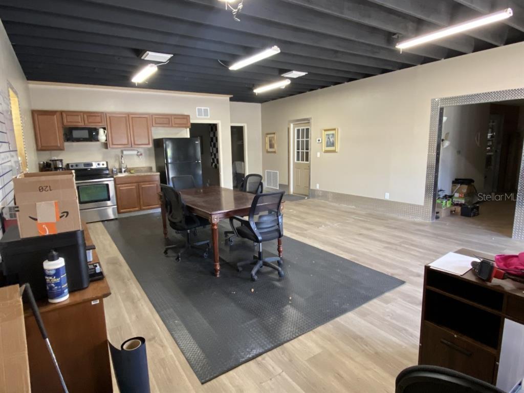 A room with a kitchen, dining table, and exposed black ceiling beams over wood flooring — 7800 SE 129TH PLACE, SUMMERFIELD, FL