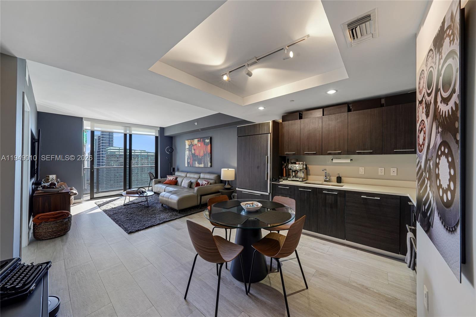 A modern open-concept living area features a kitchen, dining table, and sofa with city views — 45 SW 9th St # 3405, Miami FL 33130, MIAMI, FL