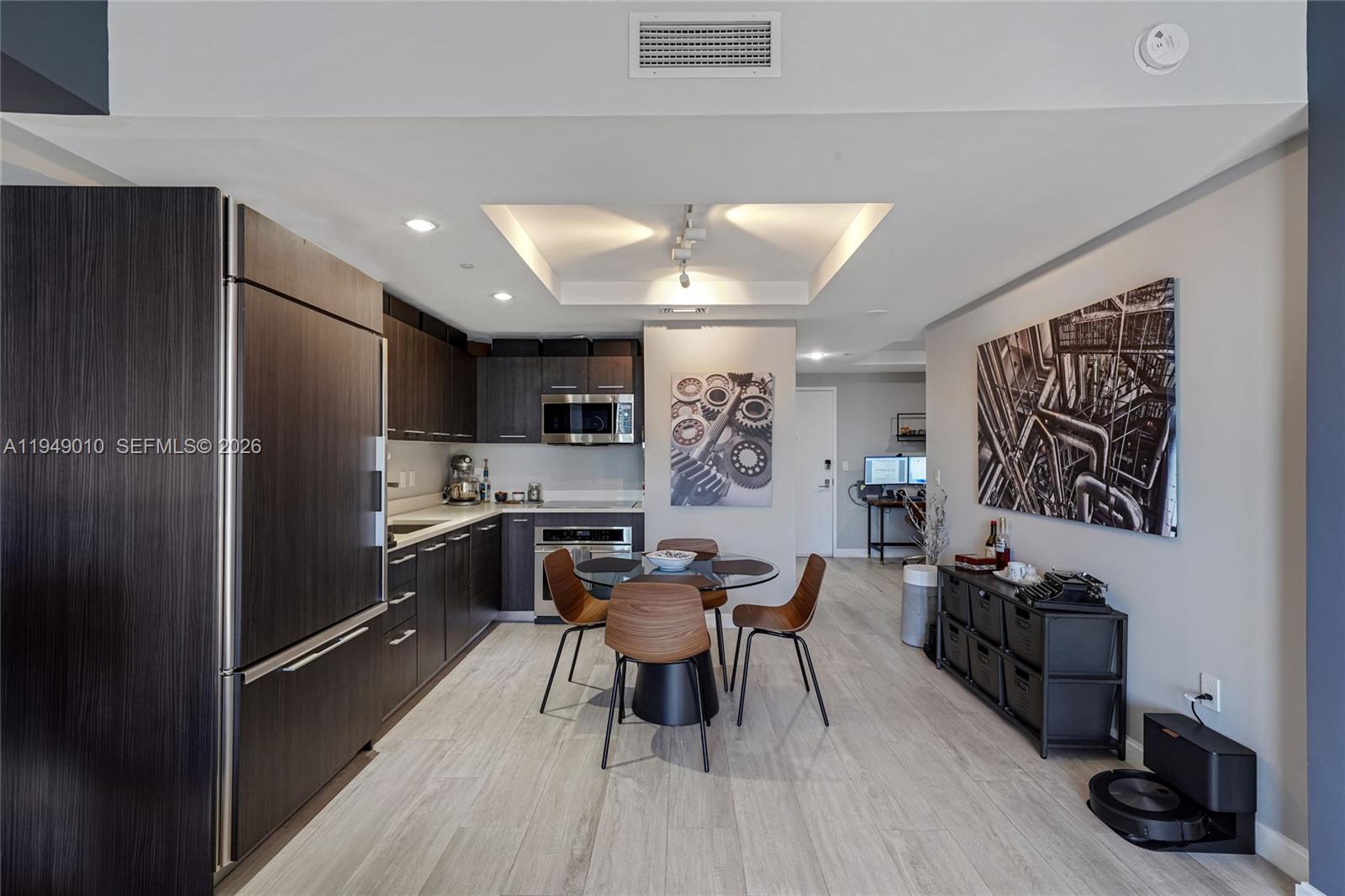 A modern kitchen and dining area feature dark wood cabinetry, stainless steel appliances, and wood-look flooring — 45 SW 9th St # 3405, Miami FL 33130, MIAMI, FL