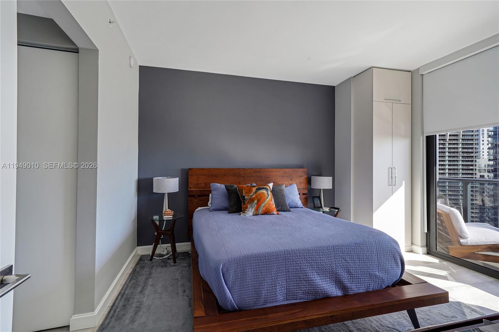 A bedroom features a dark accent wall, a wooden platform bed, and a balcony view — 45 SW 9th St # 3405, Miami FL 33130, MIAMI, FL
