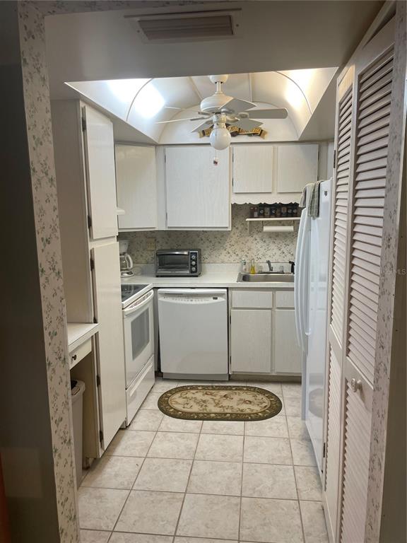 A galley kitchen features white cabinets, tile flooring, a ceiling fan, and white appliances — 532 MIDWAY DRIVE Unit A, OCALA, FL