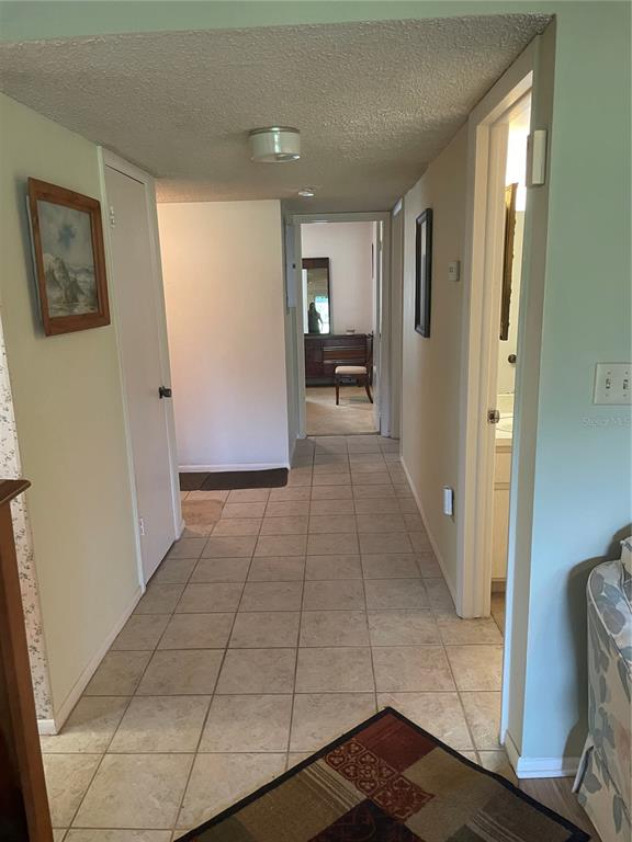 A hallway with beige tile flooring leads to a bedroom and a bathroom — 532 MIDWAY DRIVE Unit A, OCALA, FL