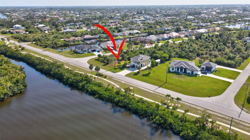 An aerial view shows a two-story house with a driveway located near a canal — 15645 SEAFOAM CIRCLE, PORT CHARLOTTE, FL