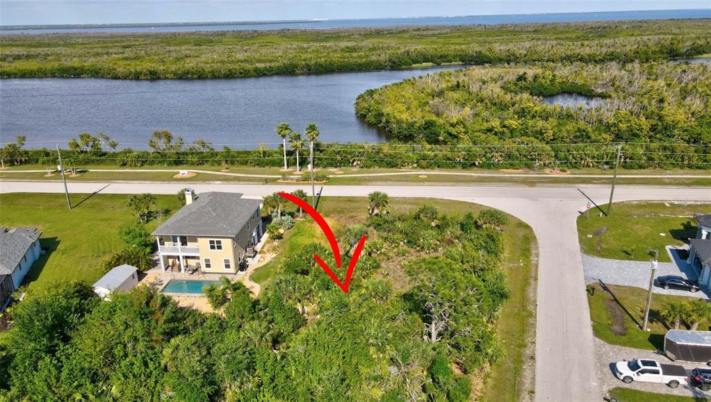 An aerial view shows a vacant, wooded lot next to a house with a pool — 15645 SEAFOAM CIRCLE, PORT CHARLOTTE, FL