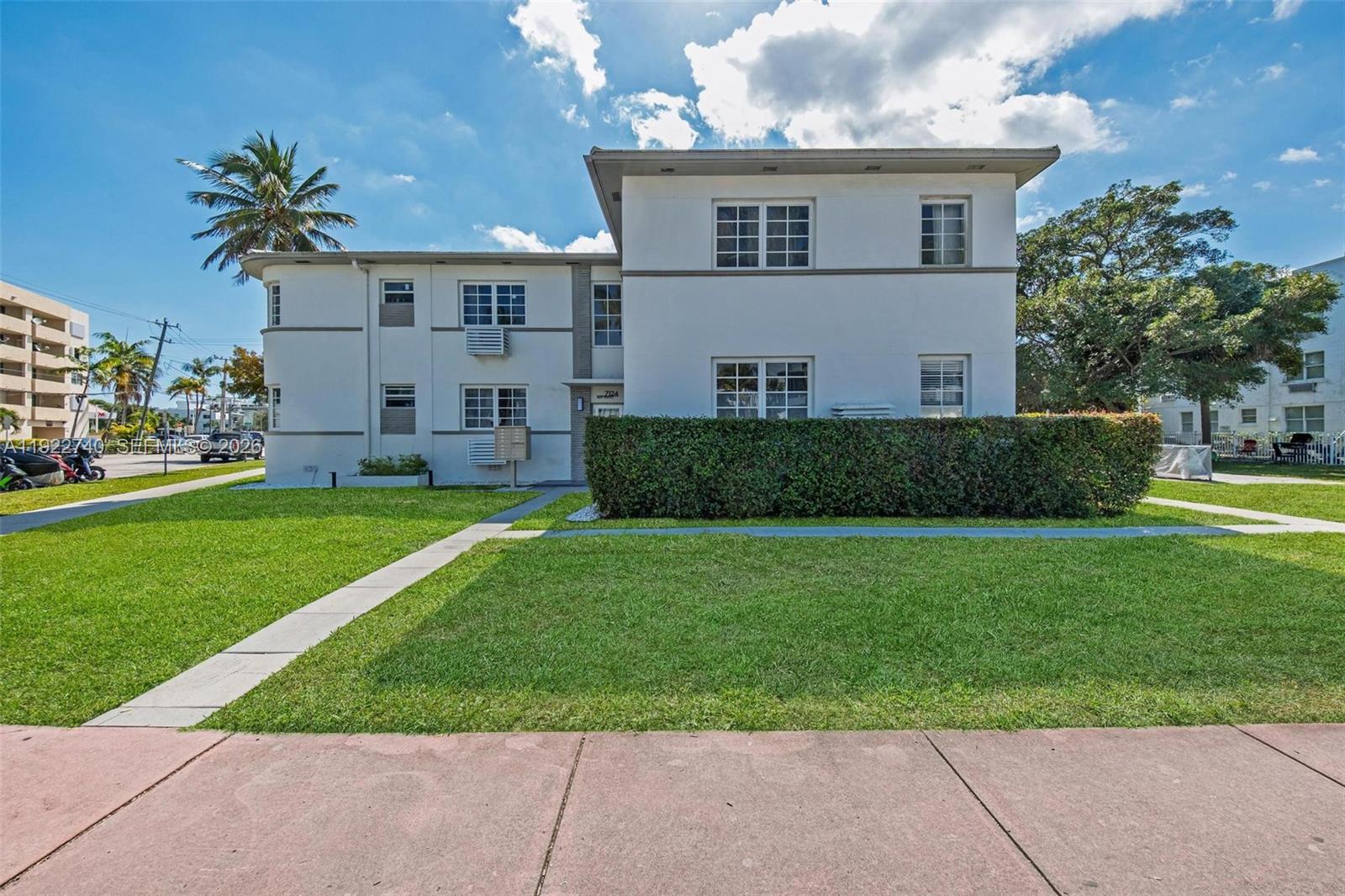 A two-story white apartment building features a manicured hedge and a front lawn — 7124 Bay Dr, Miami Beach FL 33141, MIAMI BEACH, FL
