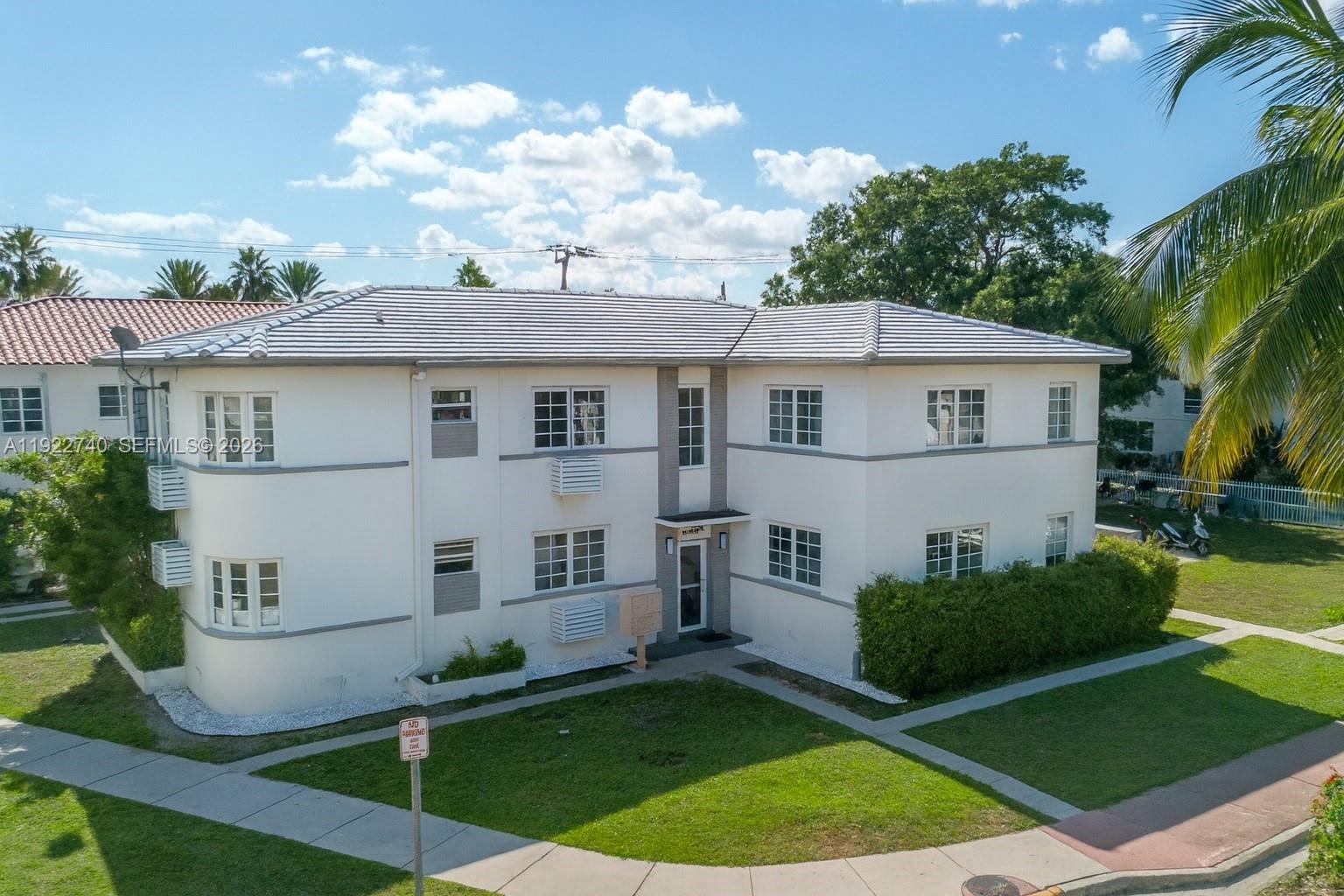 An exterior view of a two-story white apartment building with a tiled roof — 7124 Bay Dr, Miami Beach FL 33141, MIAMI BEACH, FL