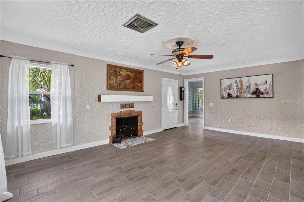 A living room features a fireplace, tile flooring, a ceiling fan, and a white door — 1830 9TH AVENUE W, BRADENTON, FL