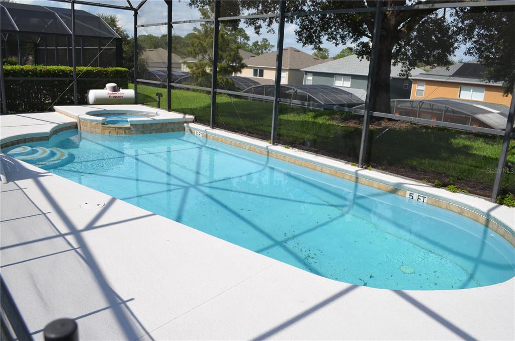 A swimming pool with an attached spa is enclosed within a screened-in patio area — 8667 LA ISLA DRIVE, KISSIMMEE, FL