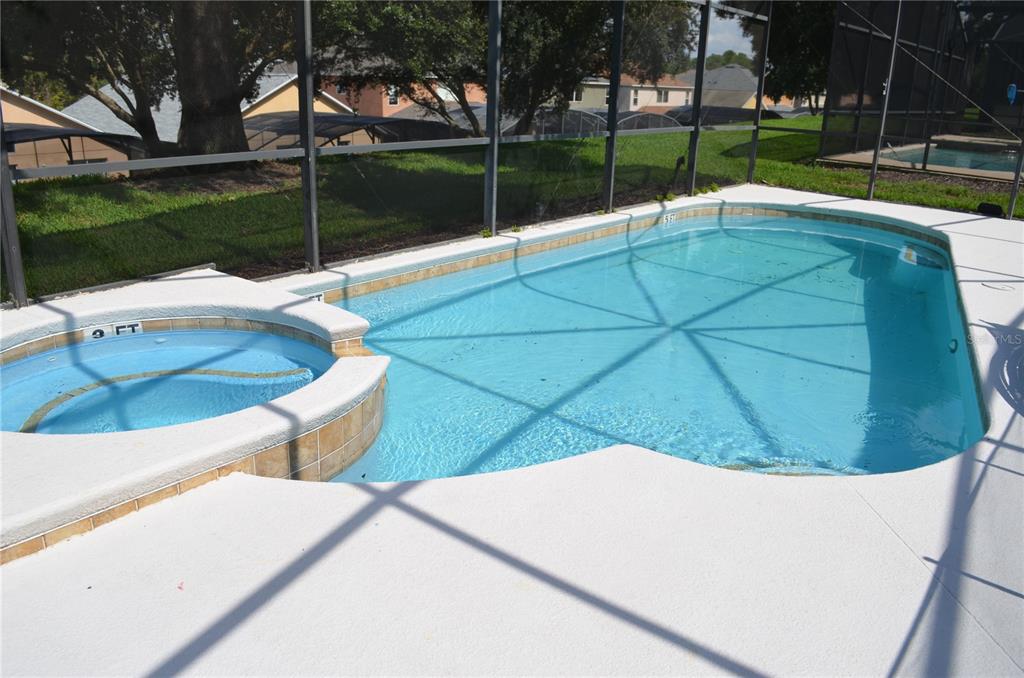 A screened-in swimming pool and attached spa are surrounded by a concrete deck — 8667 LA ISLA DRIVE, KISSIMMEE, FL