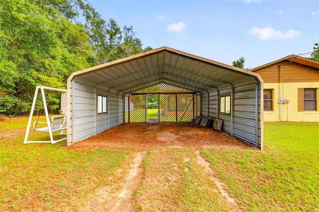 A metal carport stands on a dirt and grass lot next to a house — 15900 SE 92ND TERRACE, SUMMERFIELD, FL