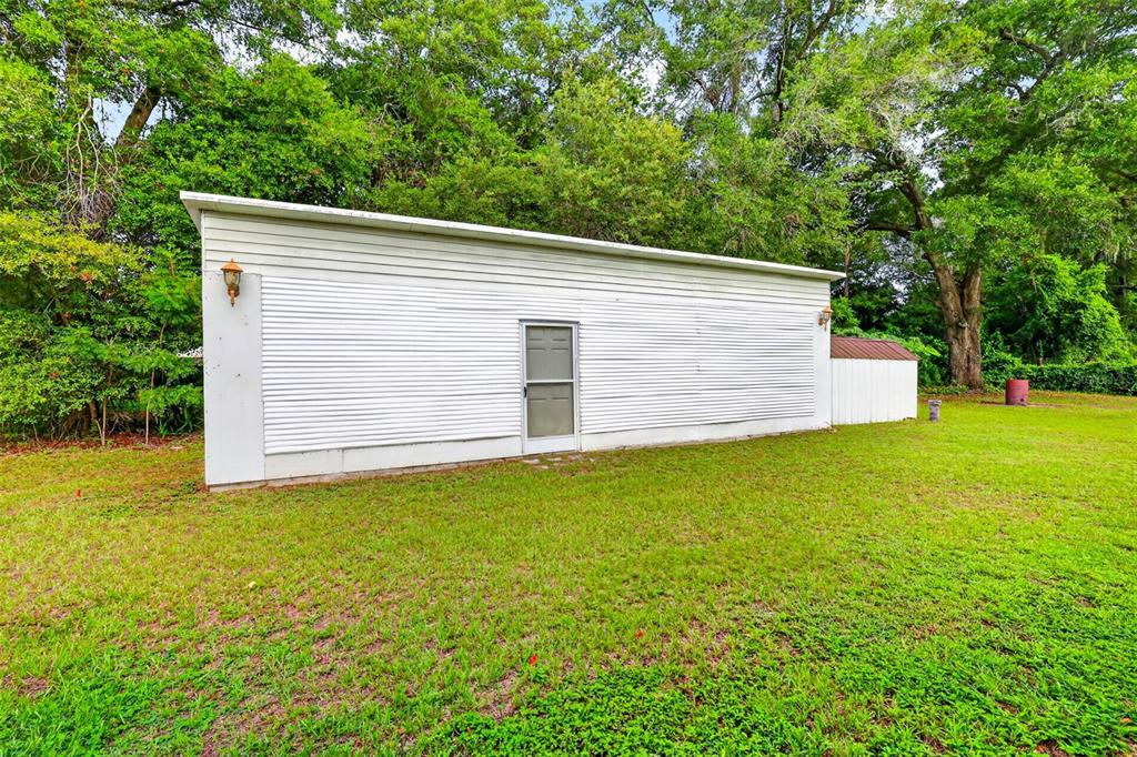 A white, single-story detached garage with a metal door stands on a grassy lawn — 15900 SE 92ND TERRACE, SUMMERFIELD, FL