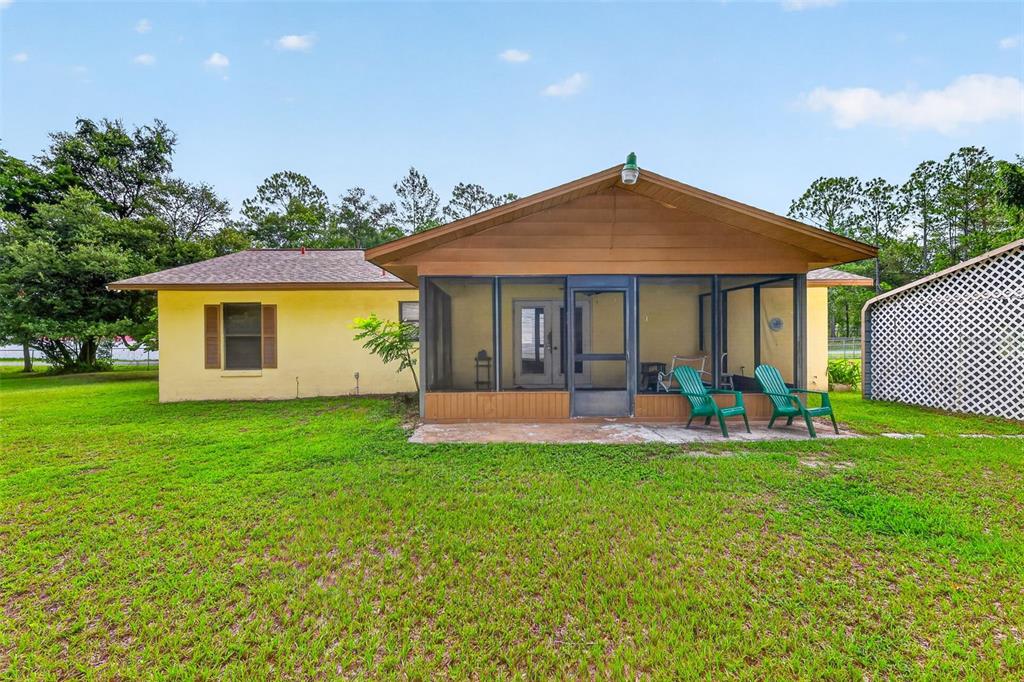 A yellow house with a screened-in porch and a large grassy backyard — 15900 SE 92ND TERRACE, SUMMERFIELD, FL