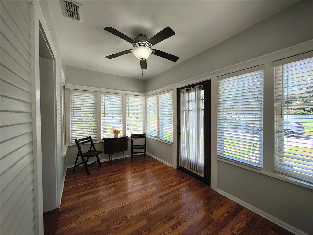 A sunroom with hardwood floors, a ceiling fan, and multiple windows with white blinds — 708 W IDLEWILD AVENUE, TAMPA, FL