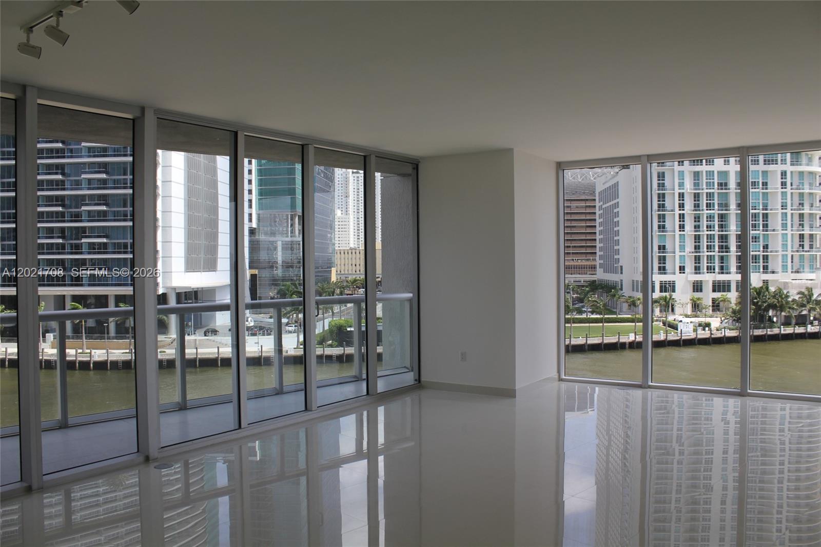 An empty room with white tile floors and floor-to-ceiling windows overlooking a waterfront cityscape — 465 BRICKELL AV # 502, Miami FL 33131, MIAMI, FL