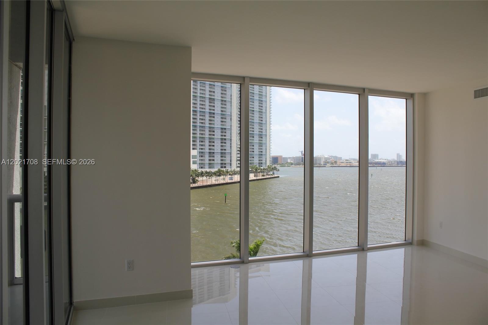 An empty room with white tile floors and floor-to-ceiling windows overlooking a bay — 465 BRICKELL AV # 502, Miami FL 33131, MIAMI, FL