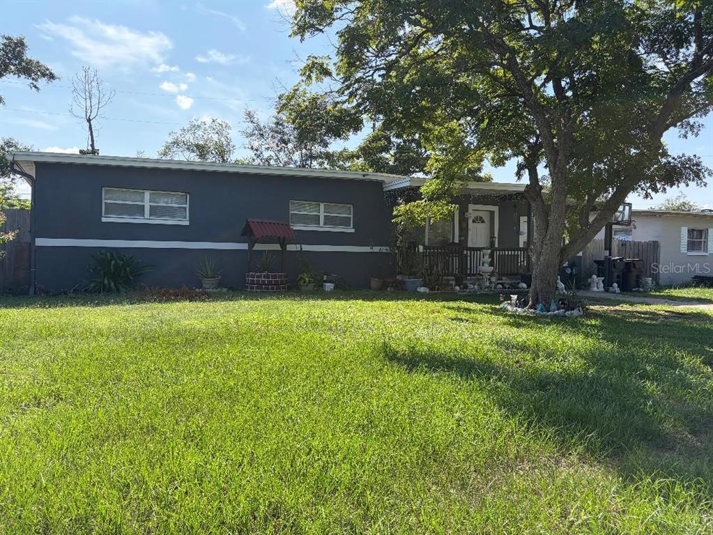 A single-story house with a dark gray exterior and a large tree in the front yard — 908 S SOLANDRA DRIVE, ORLANDO, FL