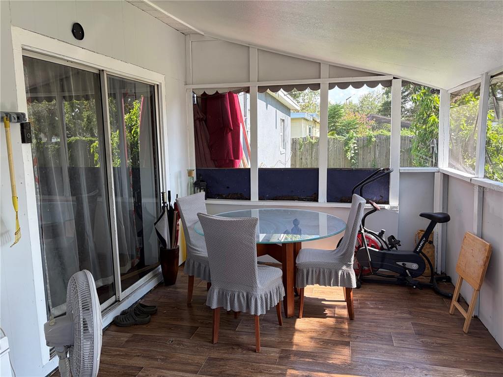 A sunroom features wood-look tile flooring, a glass-topped dining table, and an exercise bike — 908 S SOLANDRA DRIVE, ORLANDO, FL