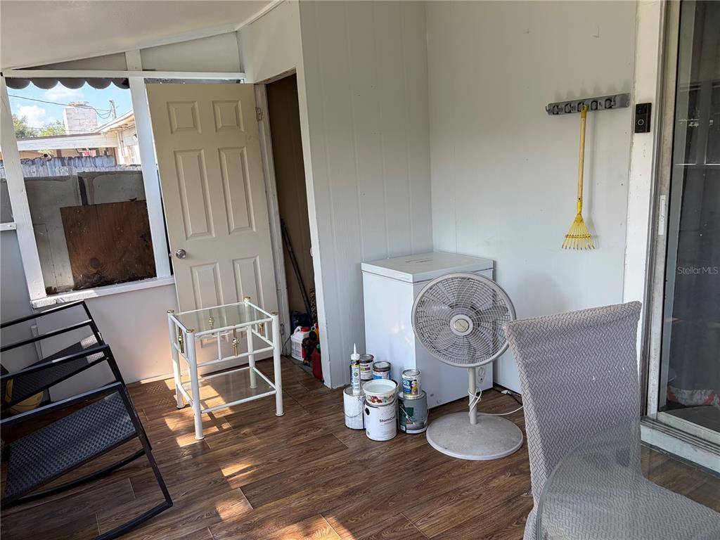 A sunroom features wood-look flooring, a chest freezer, a pedestal fan, and a storage closet — 908 S SOLANDRA DRIVE, ORLANDO, FL