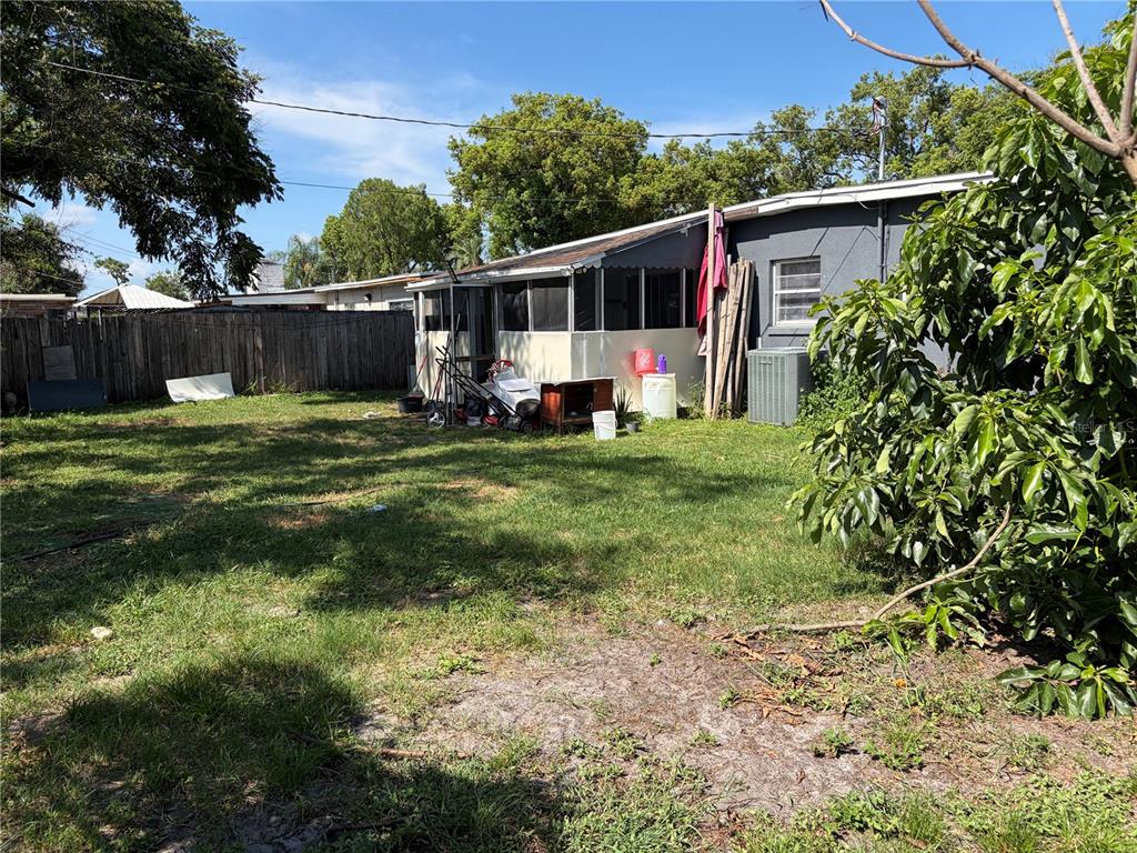 A backyard view of a house with a screened-in porch and a wooden fence — 908 S SOLANDRA DRIVE, ORLANDO, FL