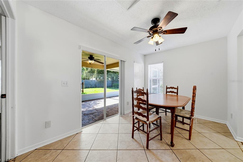 A dining area with tile floors, a wooden table, chairs, and a sliding glass door — 3828 HOLLOW OAK PLACE, LAND O LAKES, FL