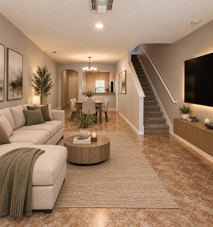 This living room features a sectional sofa, a dining area, and stairs with carpeted steps — 31150 GOSSAMER WAY, WESLEY CHAPEL, FL