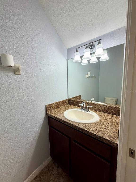 A bathroom features a dark wood vanity, granite countertop, white sink, and a wall-mounted mirror — 31150 GOSSAMER WAY, WESLEY CHAPEL, FL