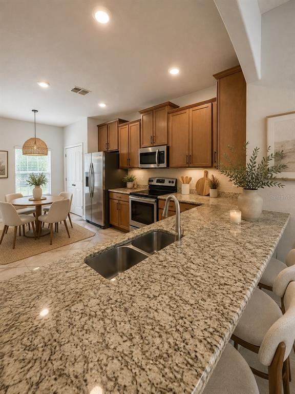 A kitchen features granite countertops, wood cabinetry, stainless steel appliances, and an adjacent dining area — 31150 GOSSAMER WAY, WESLEY CHAPEL, FL