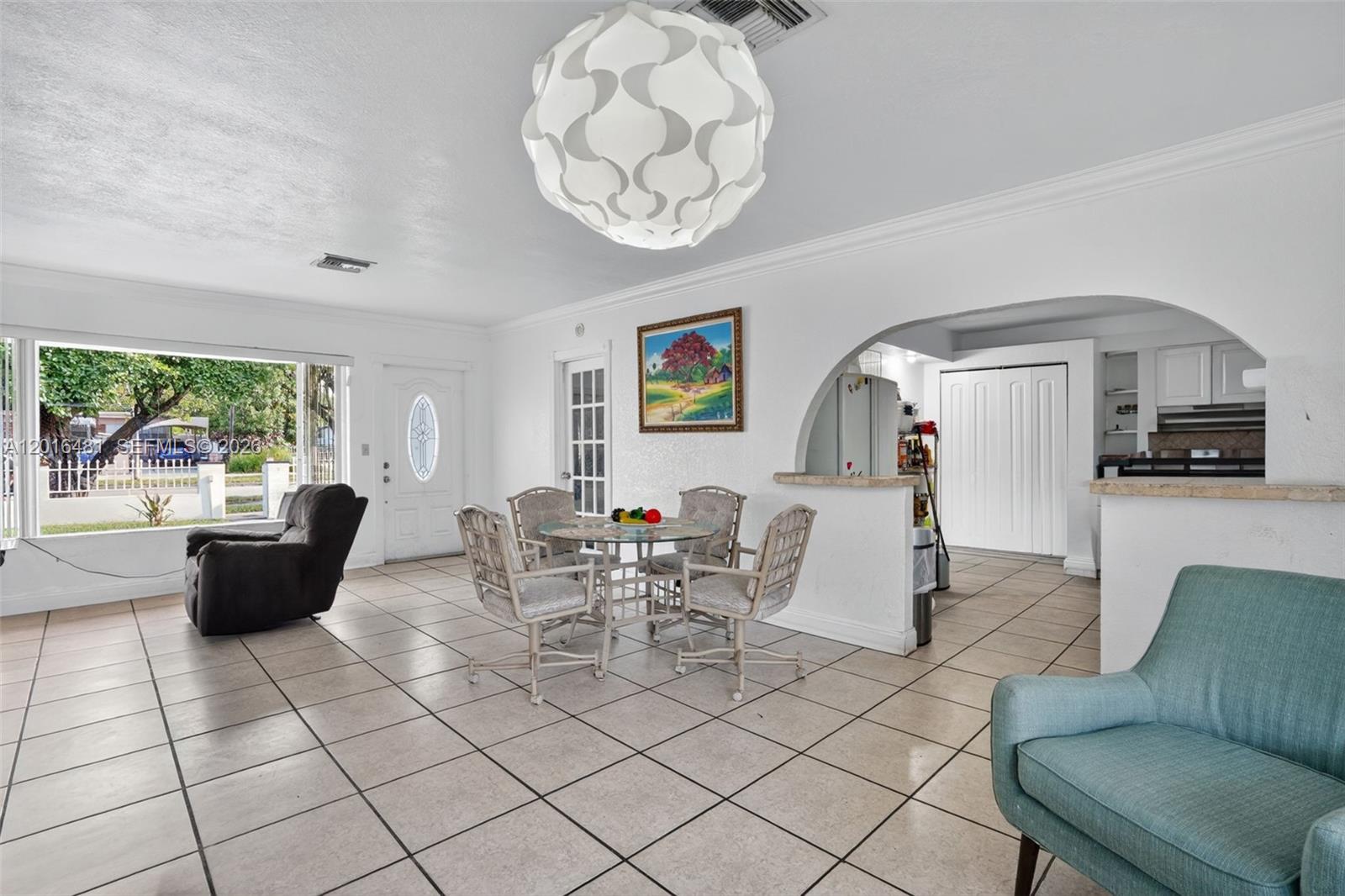 A dining area with a glass table and chairs sits next to an arched kitchen opening — 2451 NW 11th St, Miami FL 33125, MIAMI, FL