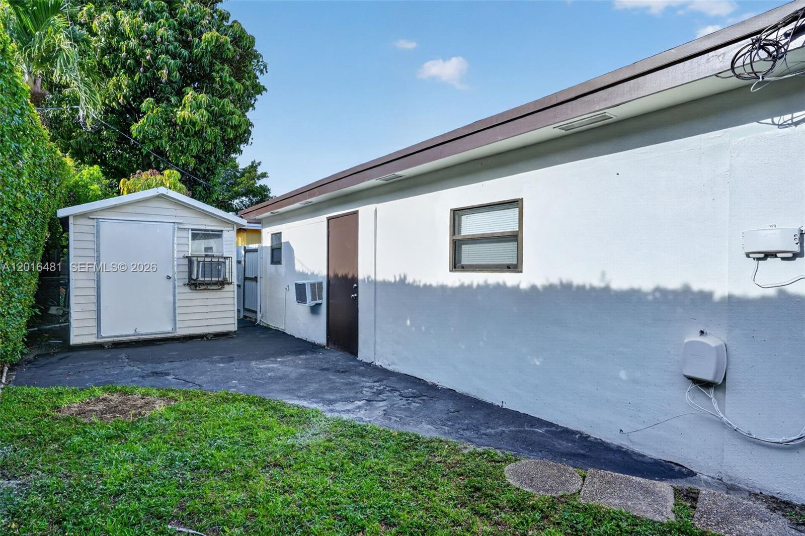 A white exterior wall with a window and door sits next to a small shed — 2451 NW 11th St, Miami FL 33125, MIAMI, FL