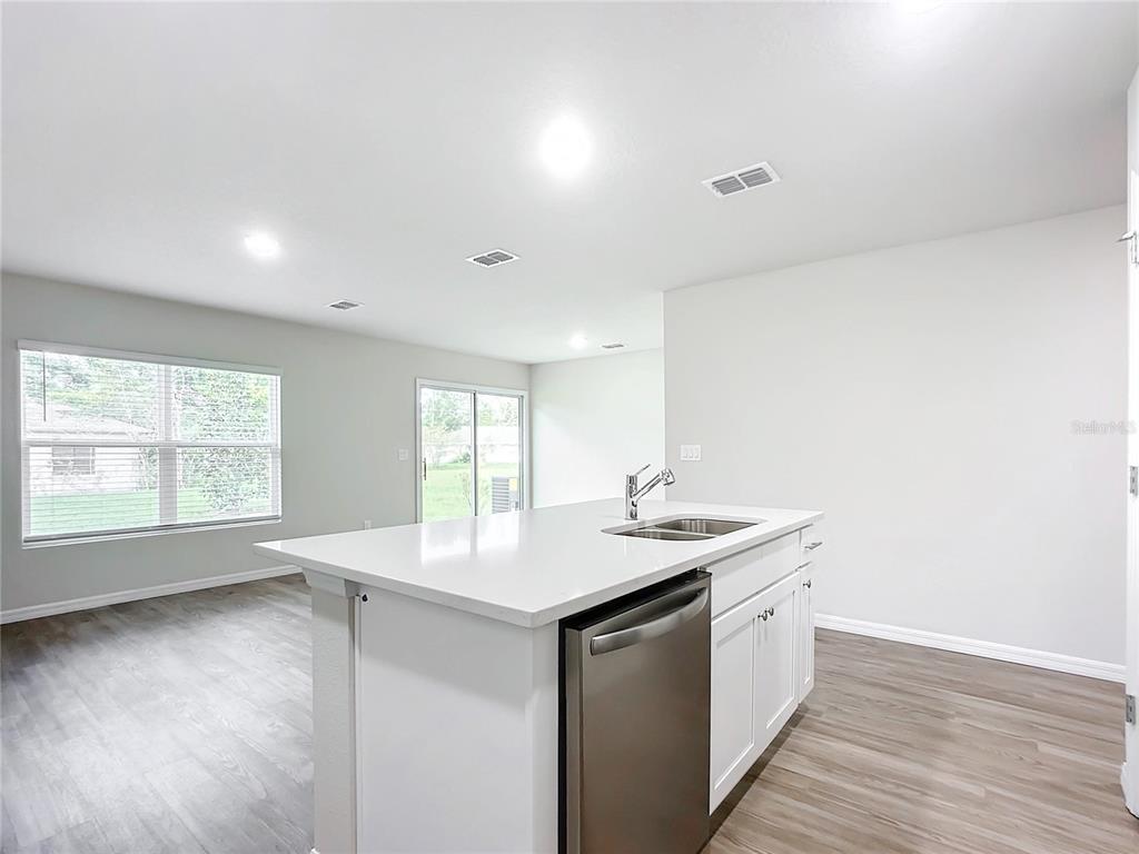 A kitchen island with a stainless steel dishwasher and sink sits in an open room — 38 SLUMBER MEADOW TRAIL, PALM COAST, FL