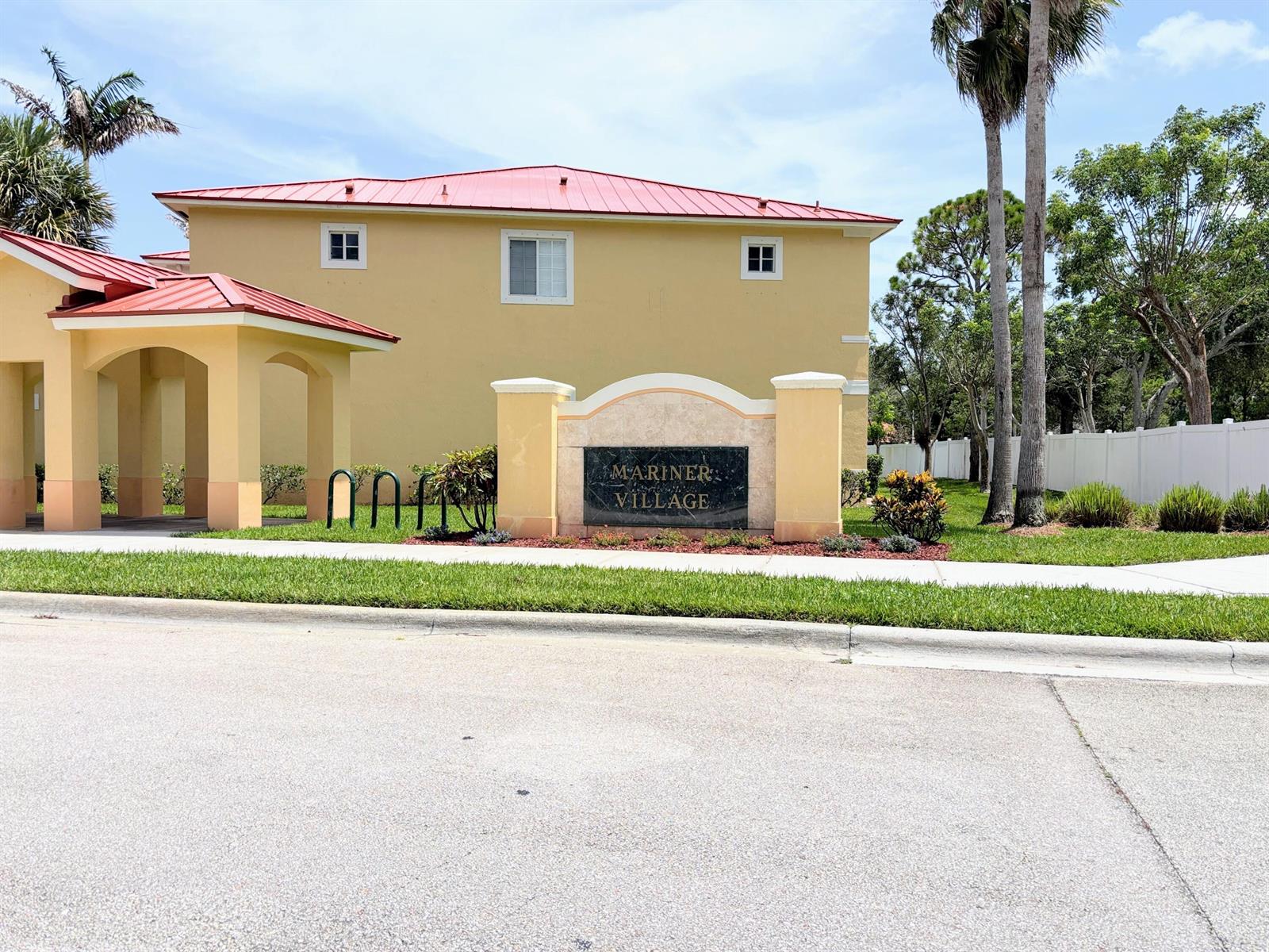 A yellow building with a red metal roof stands behind a Mariner Village entrance sign — 5088 SE Mariner Garden Circle, Stuart FL 34997, STUART, FL
