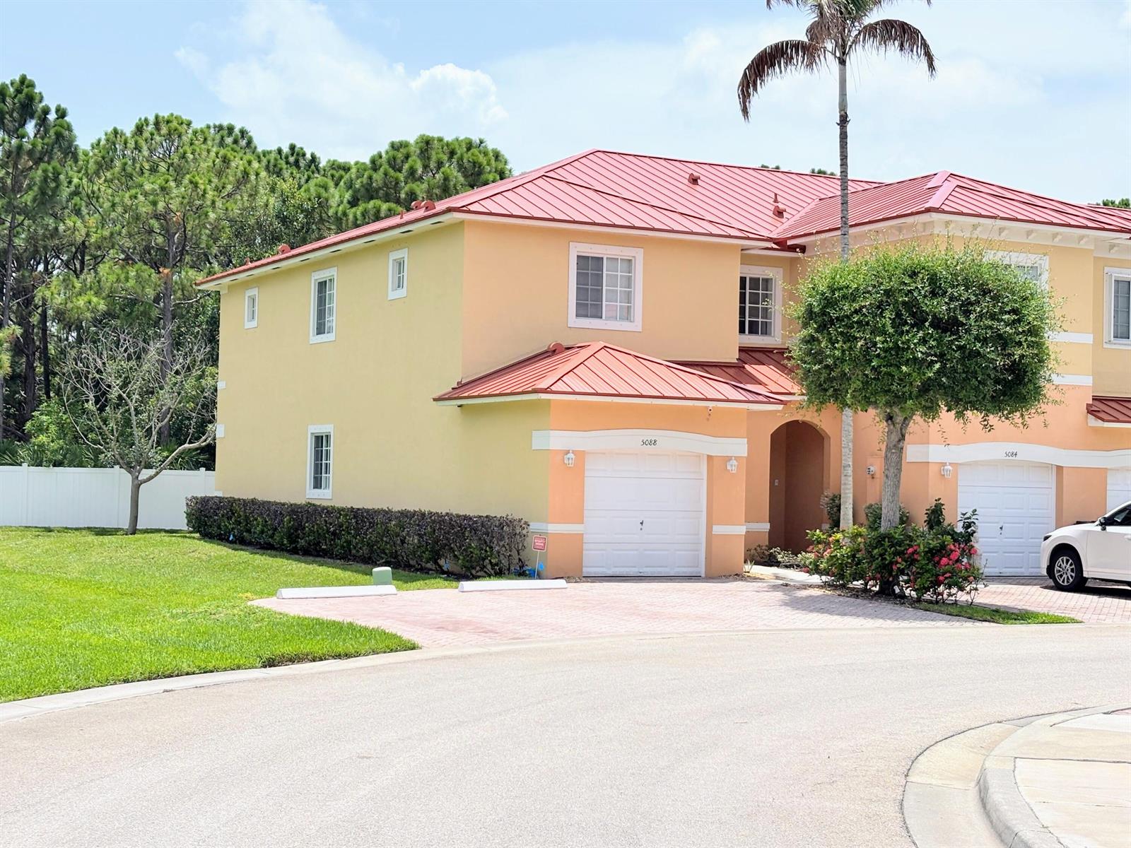 A two-story house with a red metal roof and peach-colored stucco exterior — 5088 SE Mariner Garden Circle, Stuart FL 34997, STUART, FL