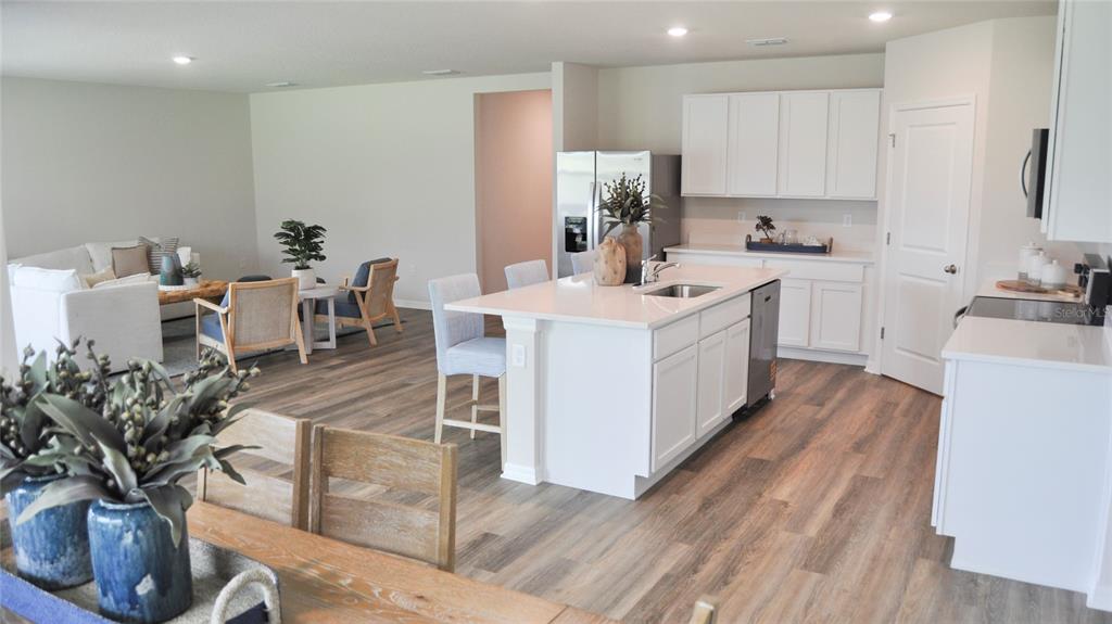 An open-concept kitchen with a white island and cabinetry overlooks a living area — 17513 WHISKEY CREEK TRAIL, PARRISH, FL