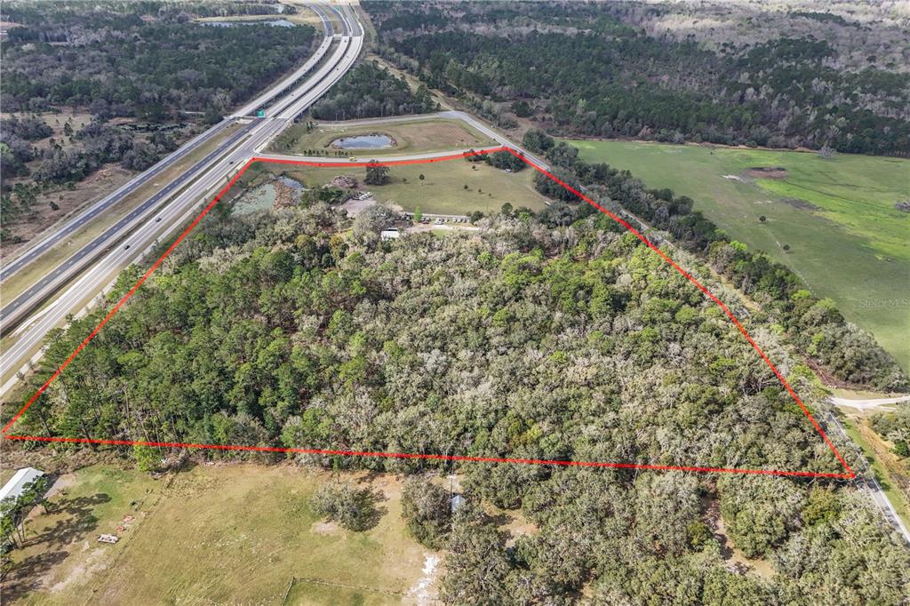 An aerial view shows a large, wooded plot of land outlined in red near a highway — 28130 CYPRESS MILL ROAD, SORRENTO, FL
