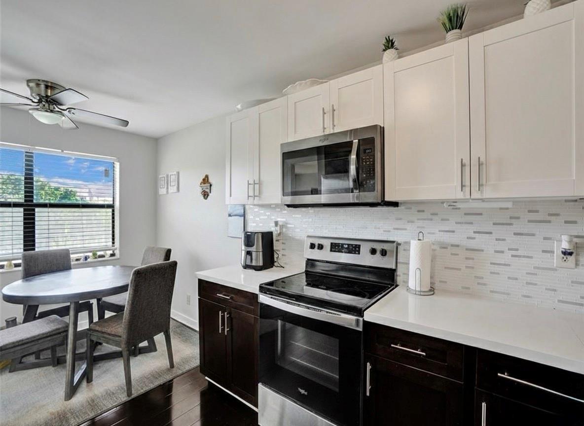 A kitchen with dark lower cabinets, white upper cabinets, stainless steel appliances, and a dining area — 2704 NW 104th Avenue # 308, Sunrise FL 33322, SUNRISE, FL
