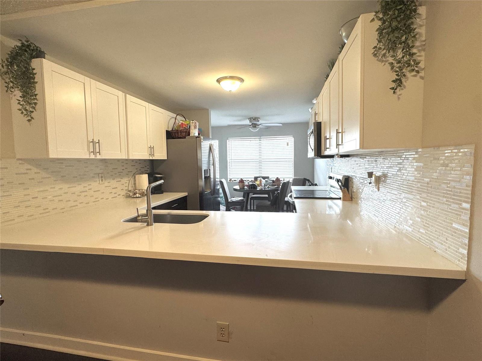 A kitchen features white cabinets, a light-colored countertop, and a tiled backsplash — 2704 NW 104th Avenue # 308, Sunrise FL 33322, SUNRISE, FL