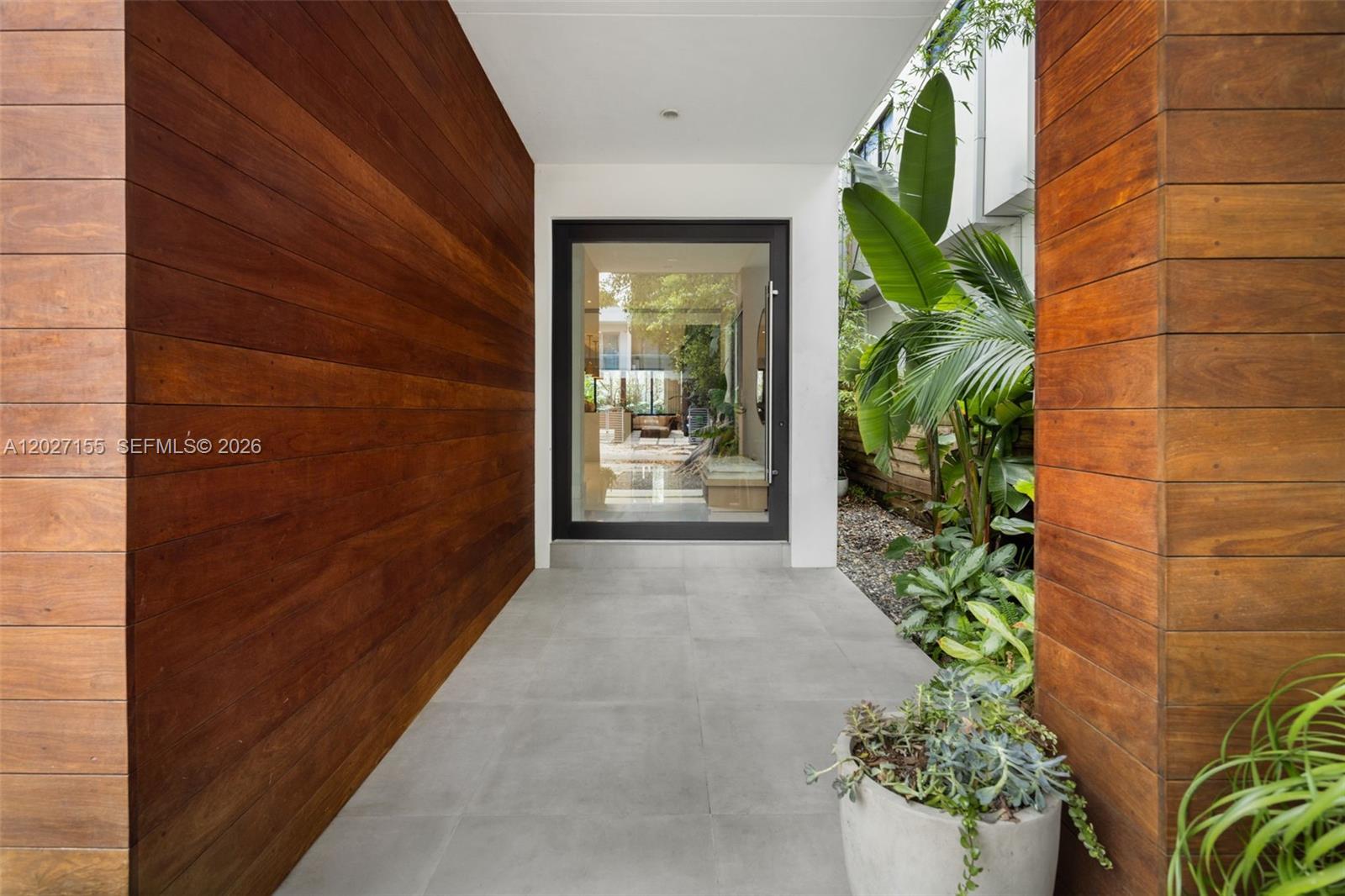 A modern entryway features wood-paneled walls, gray tile flooring, and a glass front door — 2986 Coconut Ave, Coconut Grove FL 33133, COCONUT GROVE, FL