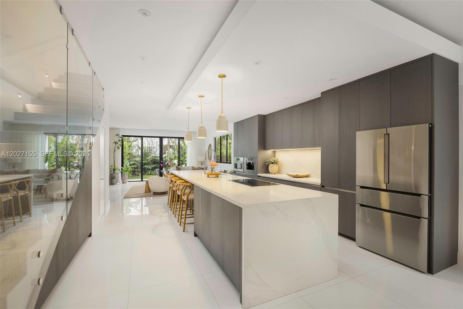 A modern kitchen features dark wood cabinetry, a large white waterfall island, and stainless appliances — 2986 Coconut Ave, Coconut Grove FL 33133, COCONUT GROVE, FL