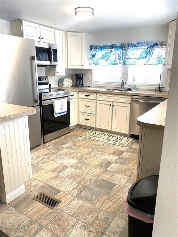 A kitchen features white cabinets, stainless steel appliances, and patterned tile flooring — 6517 ARIZONA STREET, BRADENTON, FL