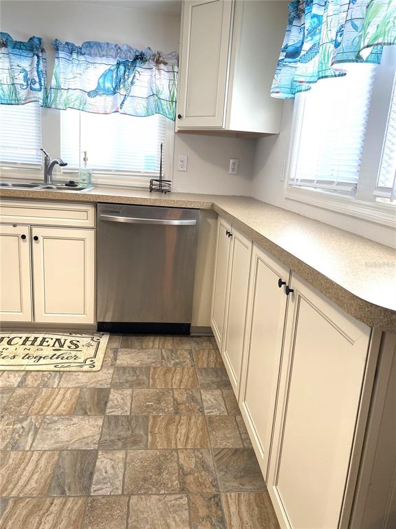 A kitchen features white cabinets, a stainless steel dishwasher, and patterned tile flooring — 6517 ARIZONA STREET, BRADENTON, FL