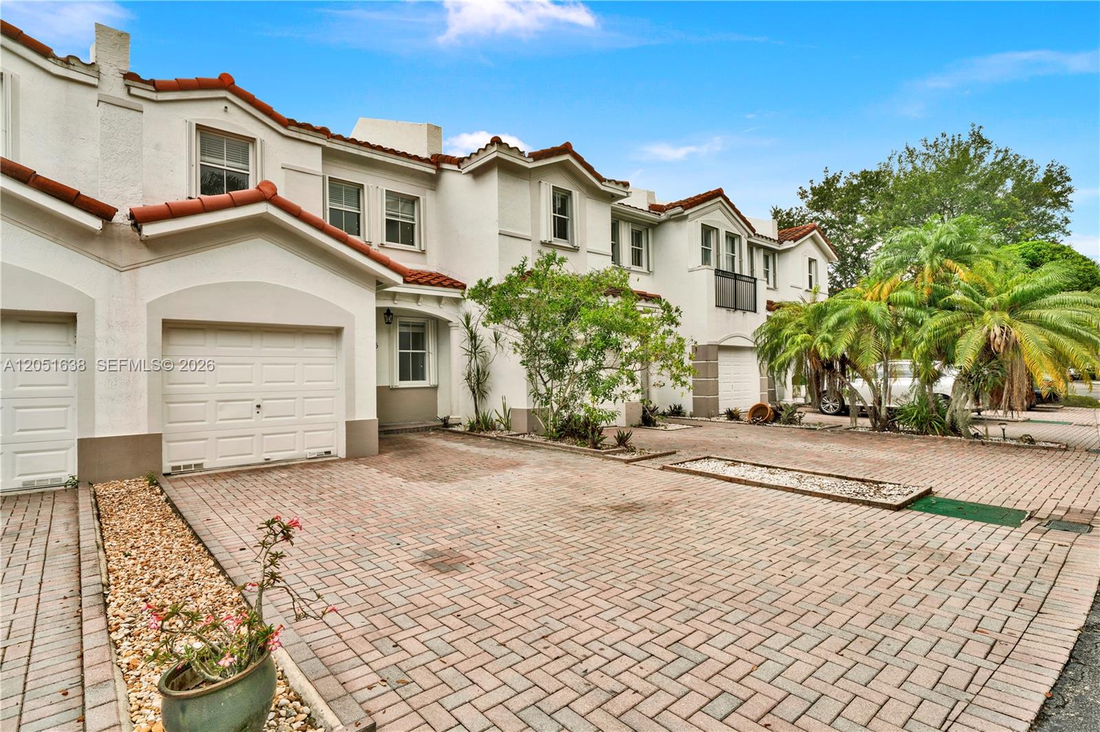The exterior of a multi-unit townhouse complex features white stucco walls, red tile roofs, and brick driveways — 11416 NW 43rd Ter, Doral FL 33178, DORAL, FL