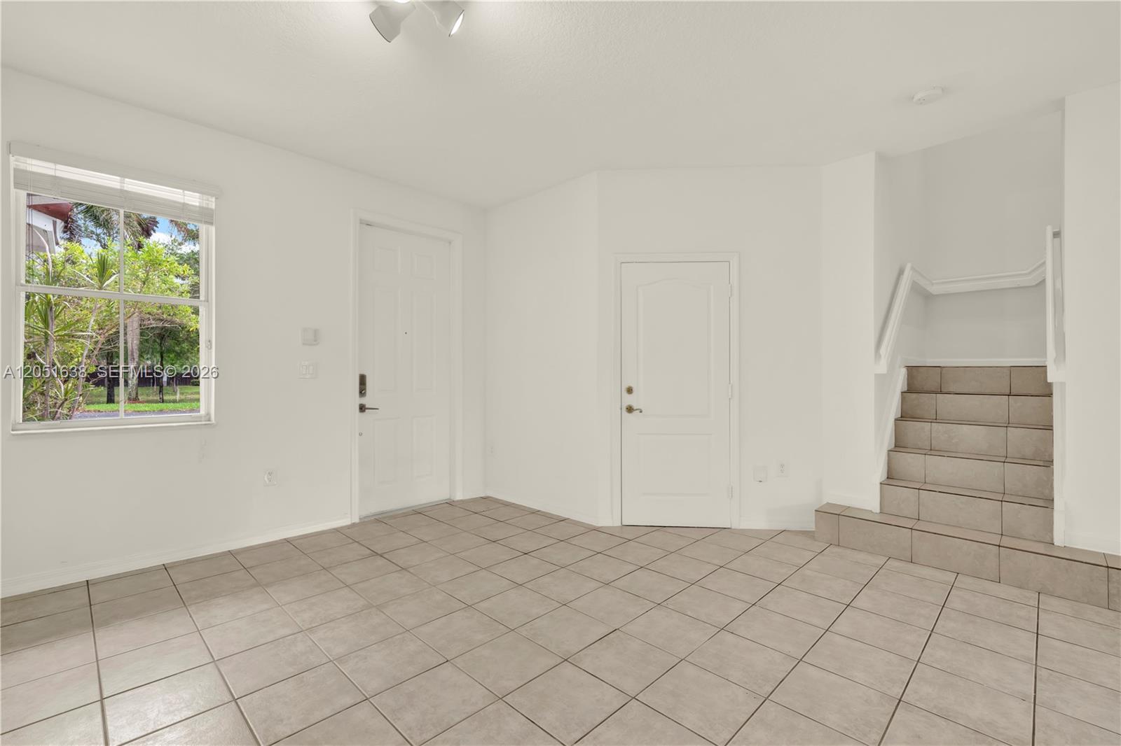 An interior view of an entryway with tiled floors, a staircase, and two white doors — 11416 NW 43rd Ter, Doral FL 33178, DORAL, FL