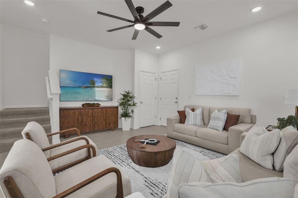 A living room features a television, a wooden console, two armchairs, and two beige sofas — 1297 STOCKWELL AVENUE, ST CLOUD, FL
