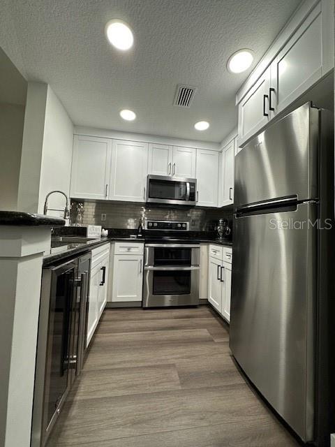 A kitchen features white cabinetry, stainless steel appliances, and wood-look flooring — 107 BRADFORD BEACH COURT UNIT 107, TAMPA, FL