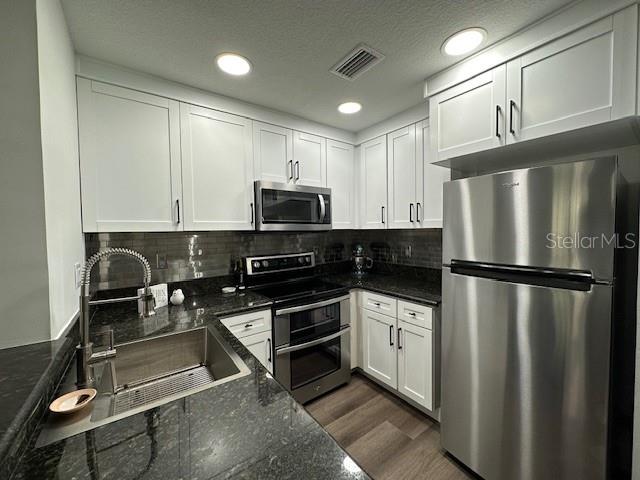A kitchen features white cabinets, stainless steel appliances, and dark granite countertops — 107 BRADFORD BEACH COURT UNIT 107, TAMPA, FL
