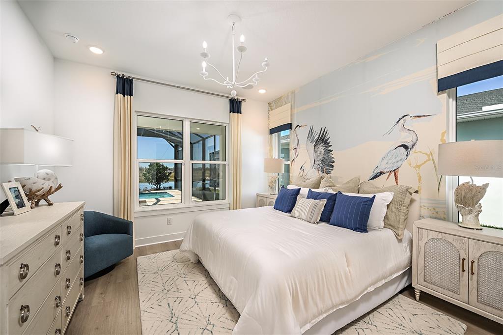 A bedroom features a bird mural, white bedding, a chandelier, and a view of a pool — 719 MALDIVES TRAIL, SARASOTA, FL