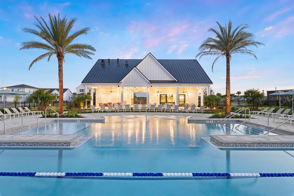 A swimming pool with lounge chairs sits in front of a modern clubhouse at dusk — 1525 RIDGEBACK LANE, APOPKA, FL
