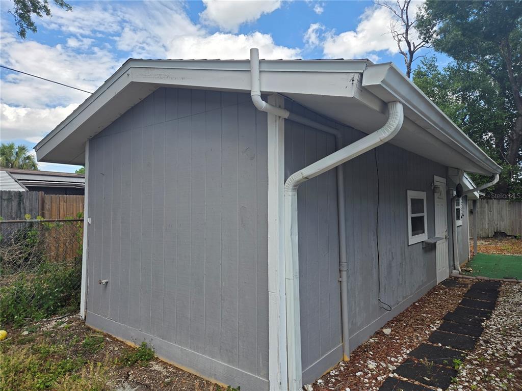 The exterior of a gray, single-story building features white trim, a downspout, and a window — 2921 W WALNUT STREET, TAMPA, FL